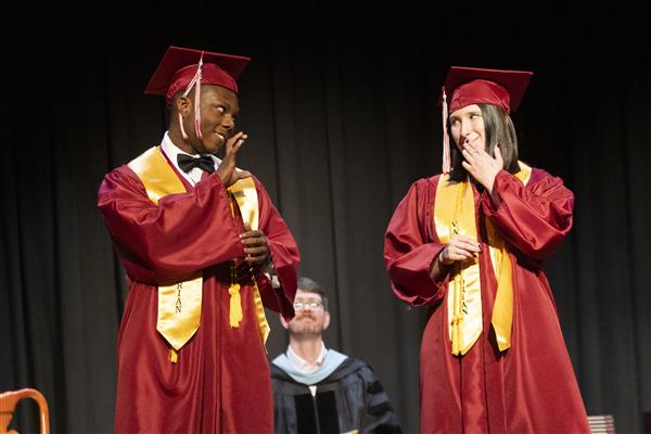 Two graduates speak to the auditorium. 